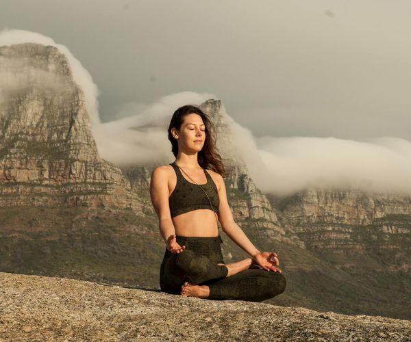Person meditating peacefully outdoors in a natural setting.